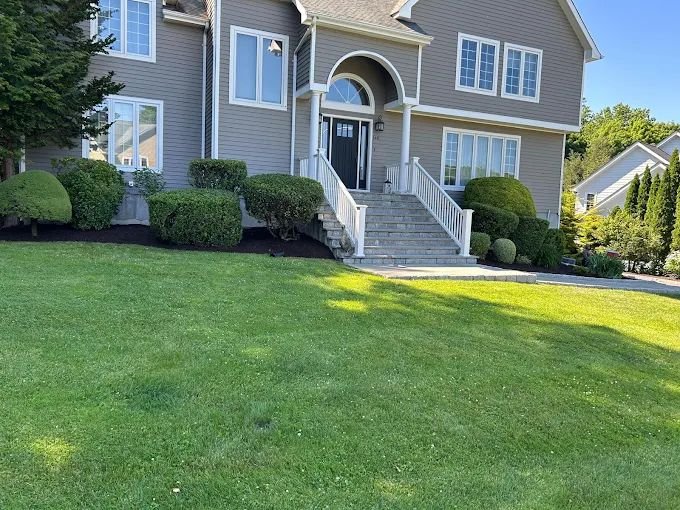 Manicured lawn, trimmed shrubs and stone front steps